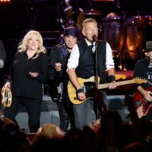 On stage, Bruce Springsteen spots a โYou Never Can Tellโ sign, quickly figures out the chords, and cues the E Street Band and horns.