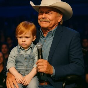 “This is the next diamond,” Alan Jackson whispered with pride in his eyes, and in that moment, his concert became something more than music—it became a beautiful glimpse into the future. The music paused as the country legend bent down to kiss his young grandson, a little boy who looked just like him, and the entire arena held its breath, witnessing not a superstar, but a grandfather sharing his legacy. It wasn’t a rehearsed part of the show; it was a raw, beautiful moment of family love playing out on the world’s stage, leaving every heart in the crowd melted and fans completely amazed by the quiet promise of what’s to come for country music.
