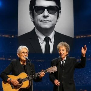 Joan Baez walked onto the stage, guitar in hand, and 70,000 fans fell into a hush. “This song is for my friend, Roy Orbison,” she said softly, as his image lit up the massive LED screen behind her.